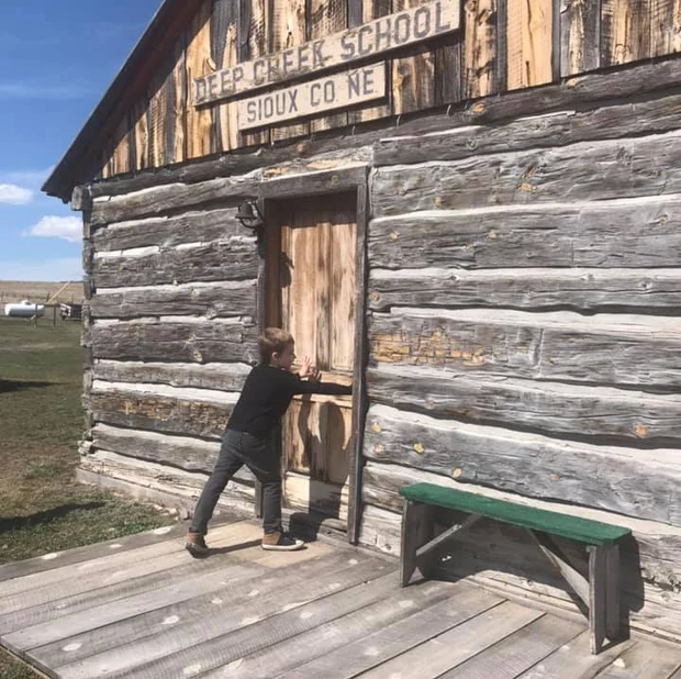 Boy pushes the door to the Old West Schoolhouse